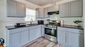 Una cocina moderna con armarios grises, estufa de acero inoxidable y salpicadero de azulejos.