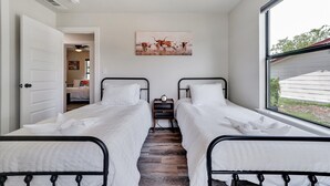 Un dormitorio con dos camas, un ventilador de techo, un cuadro de ganado y una ventana con vistas al exterior.