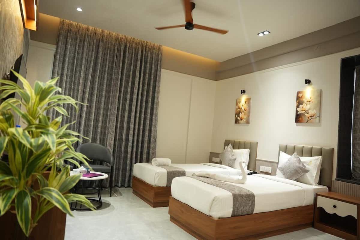A hotel room with two beds, a desk, a chair, a ceiling fan, and artwork on the walls.