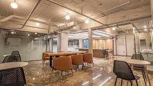 Una sala de conferencias moderna con piso de mármol, una mesa larga y varias sillas.