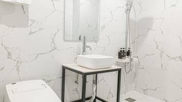 Un baño con lavamanos blanco, espejo y ducha.
