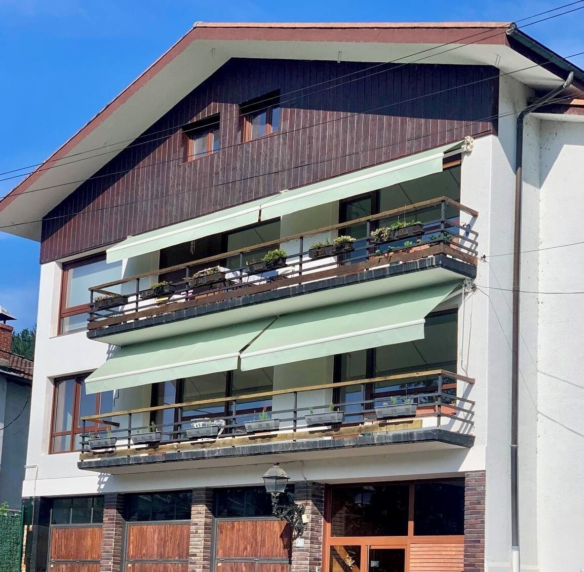 A multi-story building with balconies, a visible entrance, and a street view.