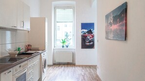 A narrow kitchen with a window, a radiator, and a sink. There are cabinets and a stove. - Near Wiener Stadthalle - 4BR Apt. w/ WIFI (Vienna)