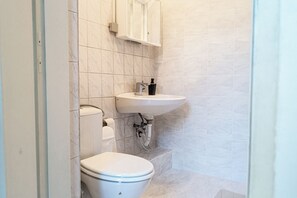A small bathroom with a toilet, sink, and a cabinet above the sink. - Near Wiener Stadthalle - 4BR Apt. w/ WIFI (Vienna)