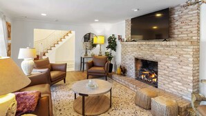 Una sala de estar con chimenea, sofás de cuero, una mesa de centro y una escalera que sube a otro nivel.