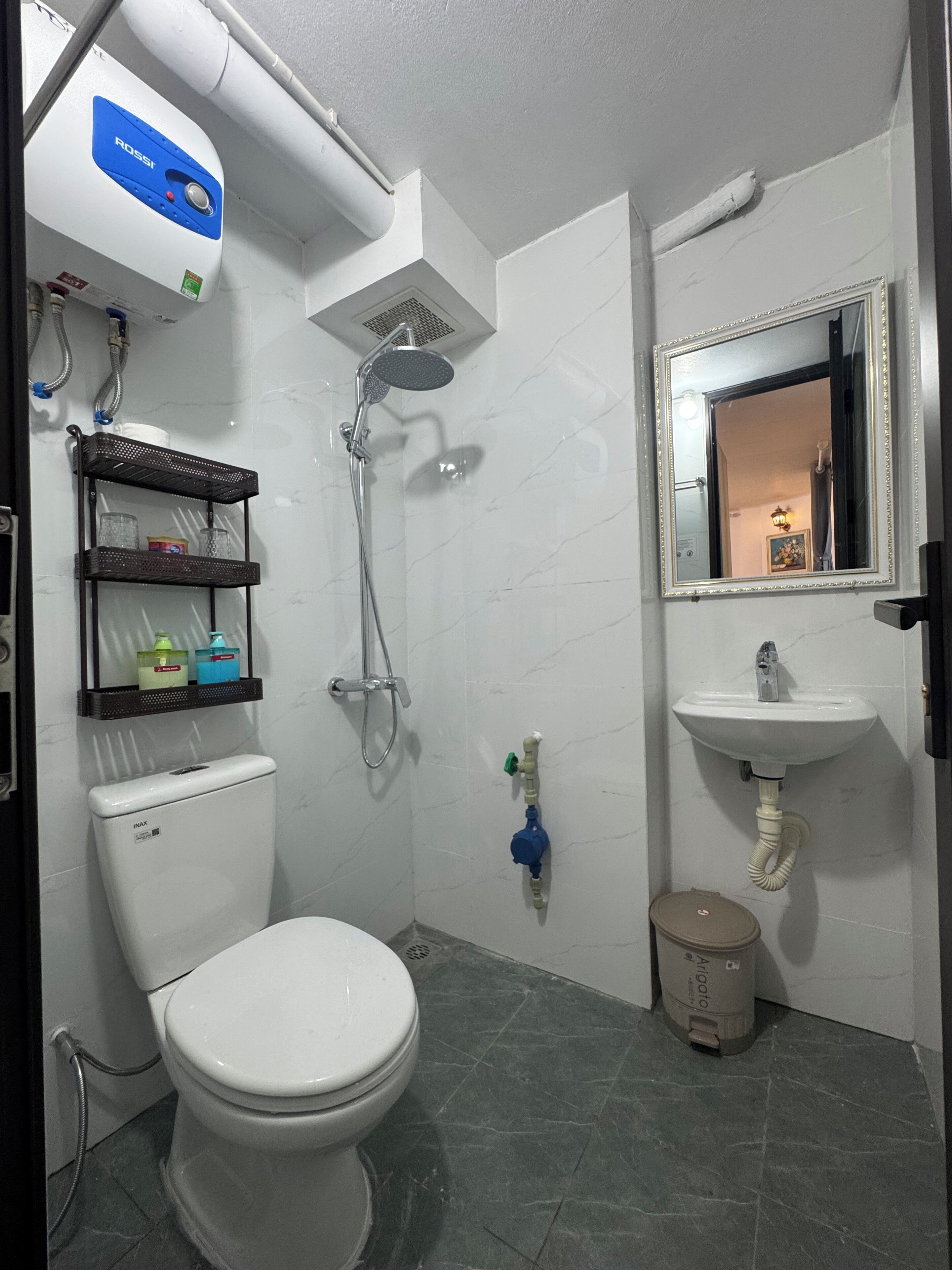 A bathroom with a toilet, a shower, a sink, and a mirror.