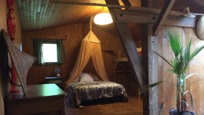 Una camera accogliente con un letto a baldacchino, soffitto in legno e una pianta in vaso.