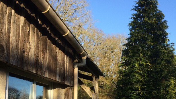 Un edificio rustico in legno con una porta in vetro e una grondaia in metallo.