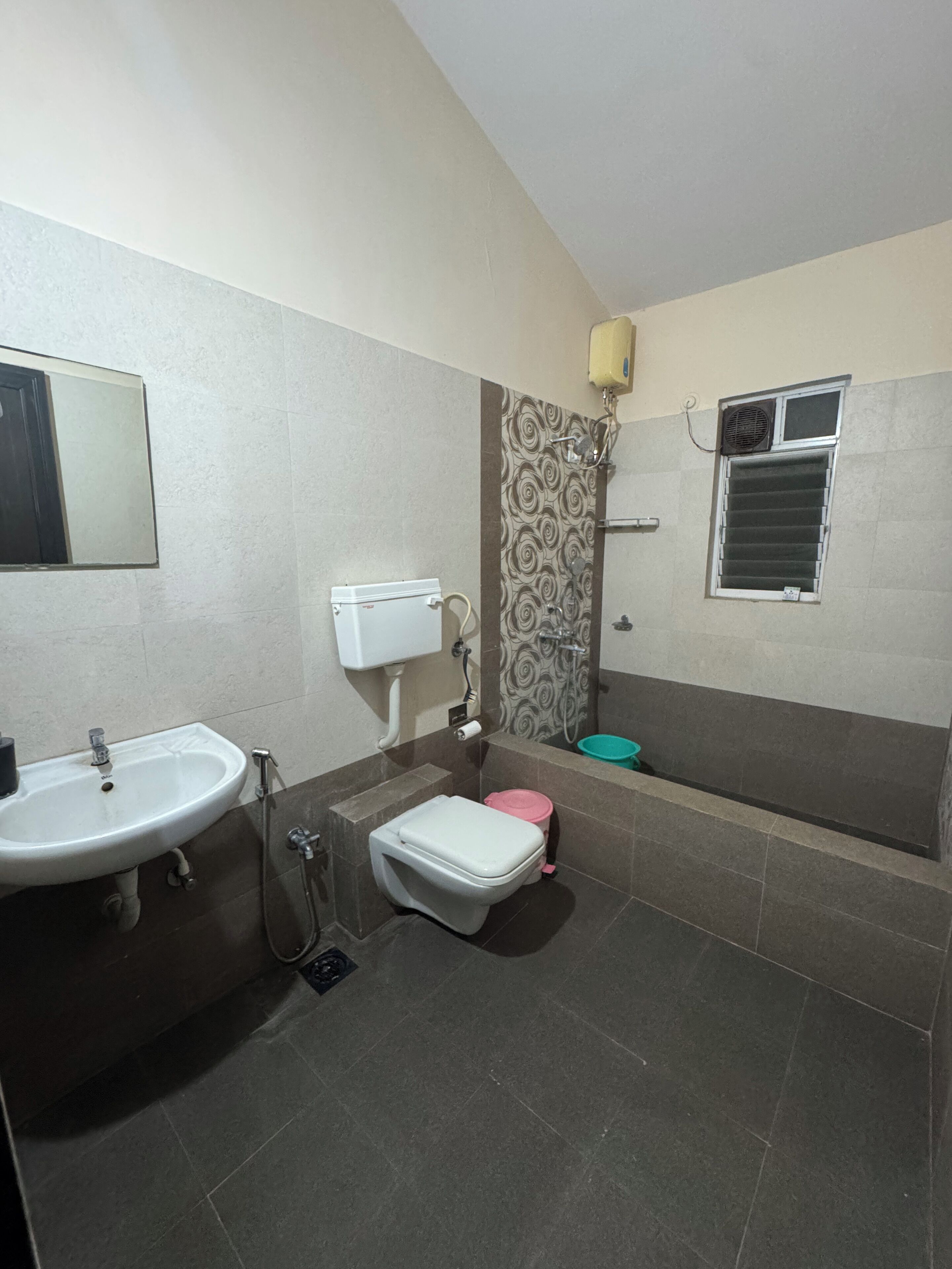 Un baño con lavamanos, inodoro, ducha y una ventana con unidad de aire acondicionado.