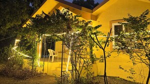 A house with a yellow exterior, a visible window, and a chair outside. - 4BHK Pool Villa In Alibaug- Anushashi's Villa (Alibag)
