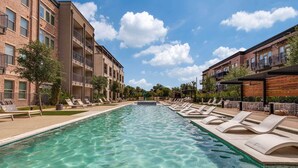 Une piscine avec des chaises longues et un bâtiment doté de balcons.