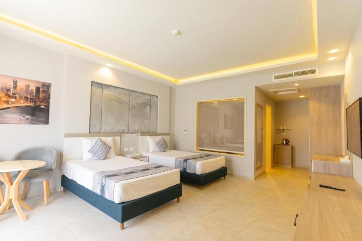 Une chambre d’hôtel moderne avec deux lits, une petite table et un téléviseur.