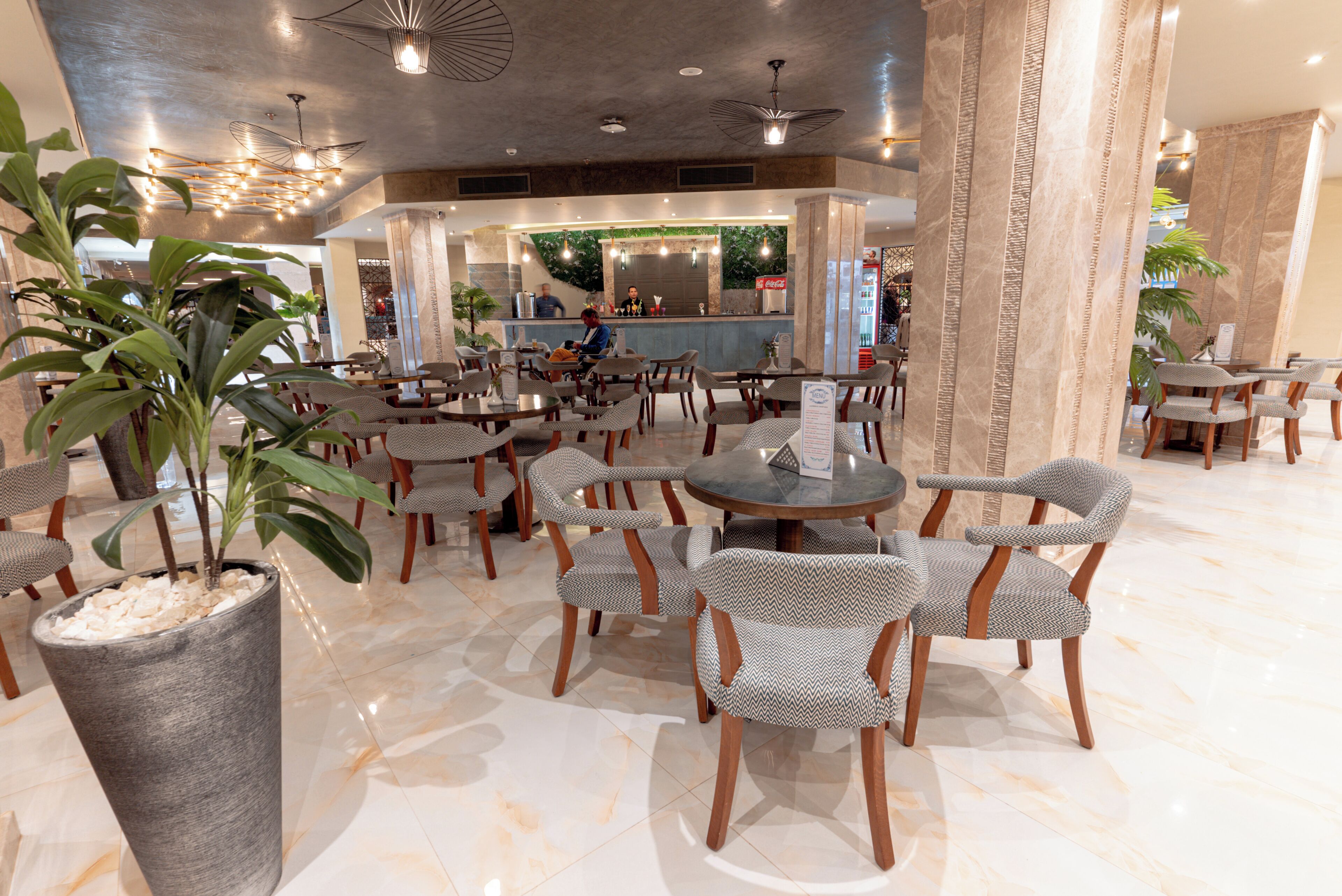 A spacious lobby with multiple seating areas, a reception desk, and decorative plants.