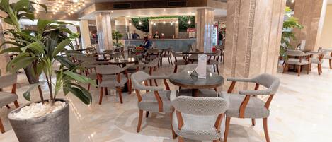 A spacious lobby with multiple seating areas, a reception desk, and decorative plants.