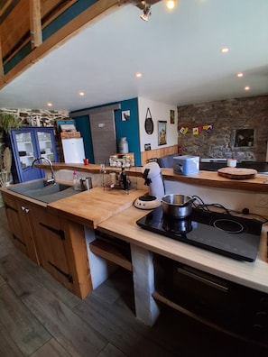 Una cocina con encimera de madera, estufa integrada, lavamanos y pared de piedra.