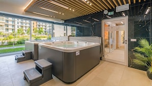 A modern spa area with two hot tubs, a glass door leading to a changing room, and a view of the outside building. - Apartamenty Sun & Snow Bałtyk Jastrzębia Góra (Jastrzębia Góra)