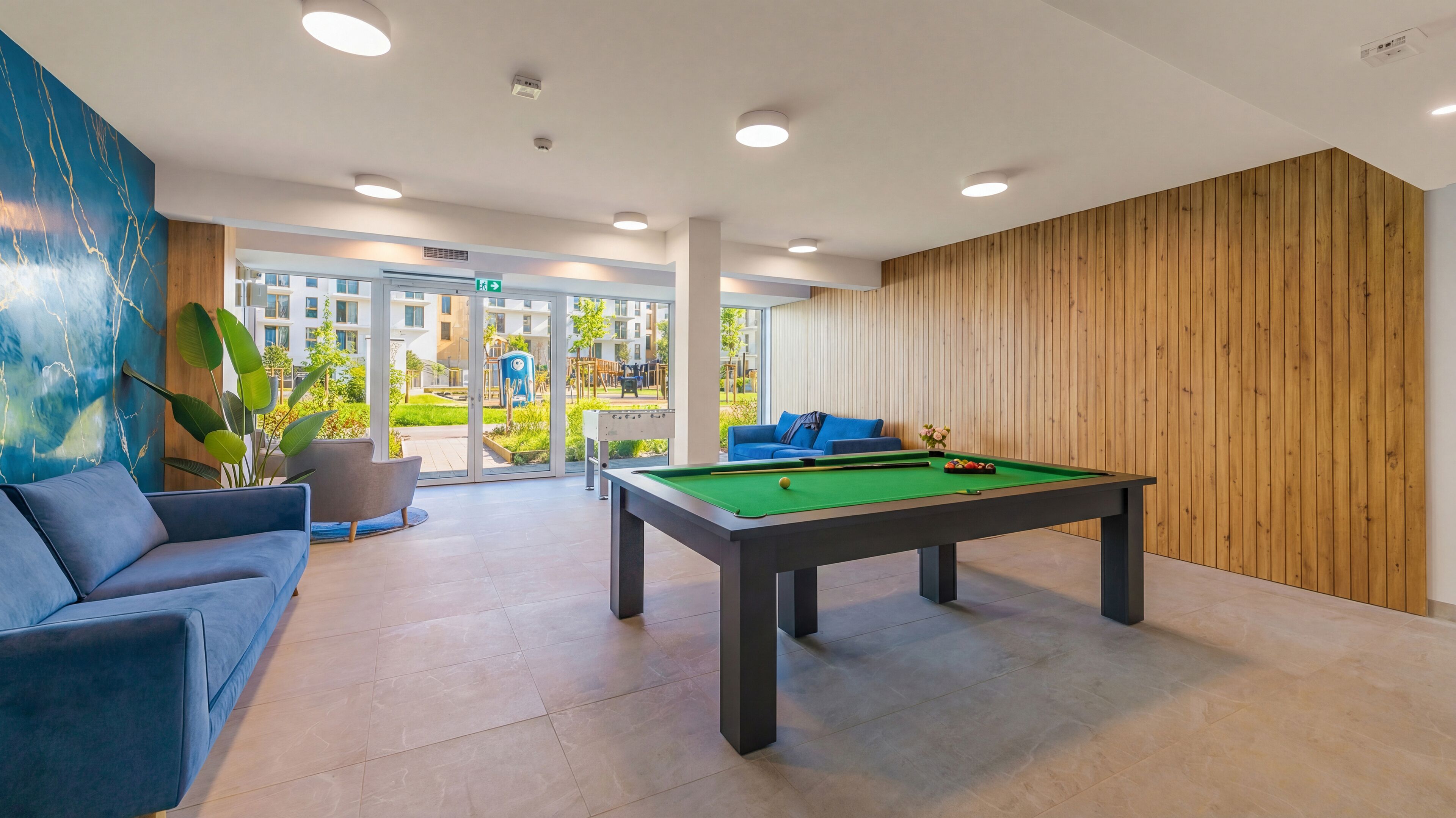 Une table de billard dans une pièce moderne, avec un canapé bleu et un mur recouvert de panneaux en bois.
