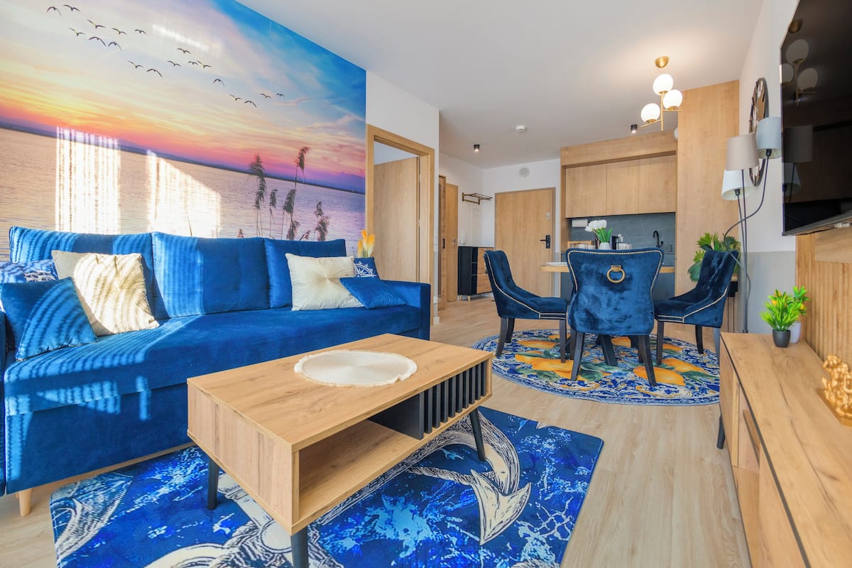 Un salon moderne avec un canapé bleu, une table basse en bois et un tapis aux couleurs vives.