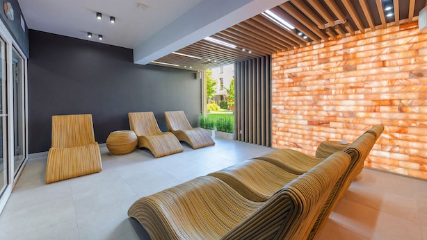 A modern lounge area with a curved sofa, a round ottoman, and a set of lounge chairs. - Apartamenty Sun & Snow Bałtyk Jastrzębia Góra (Jastrzębia Góra)