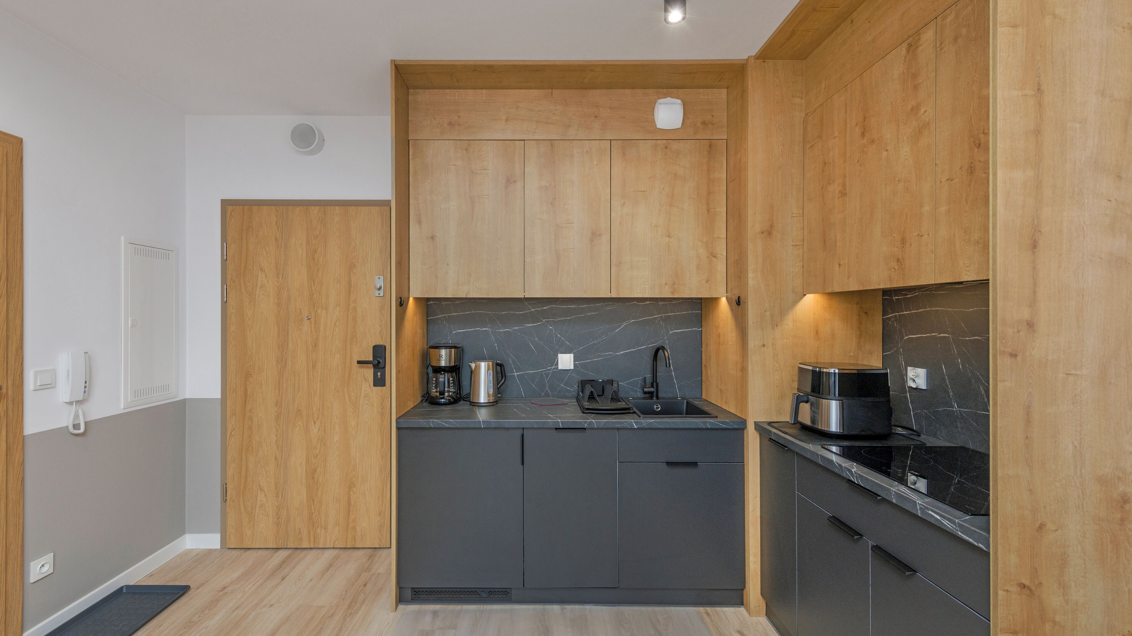 Une cuisine moderne avec des meubles en bois, un plan de travail en marbre et une machine à café.