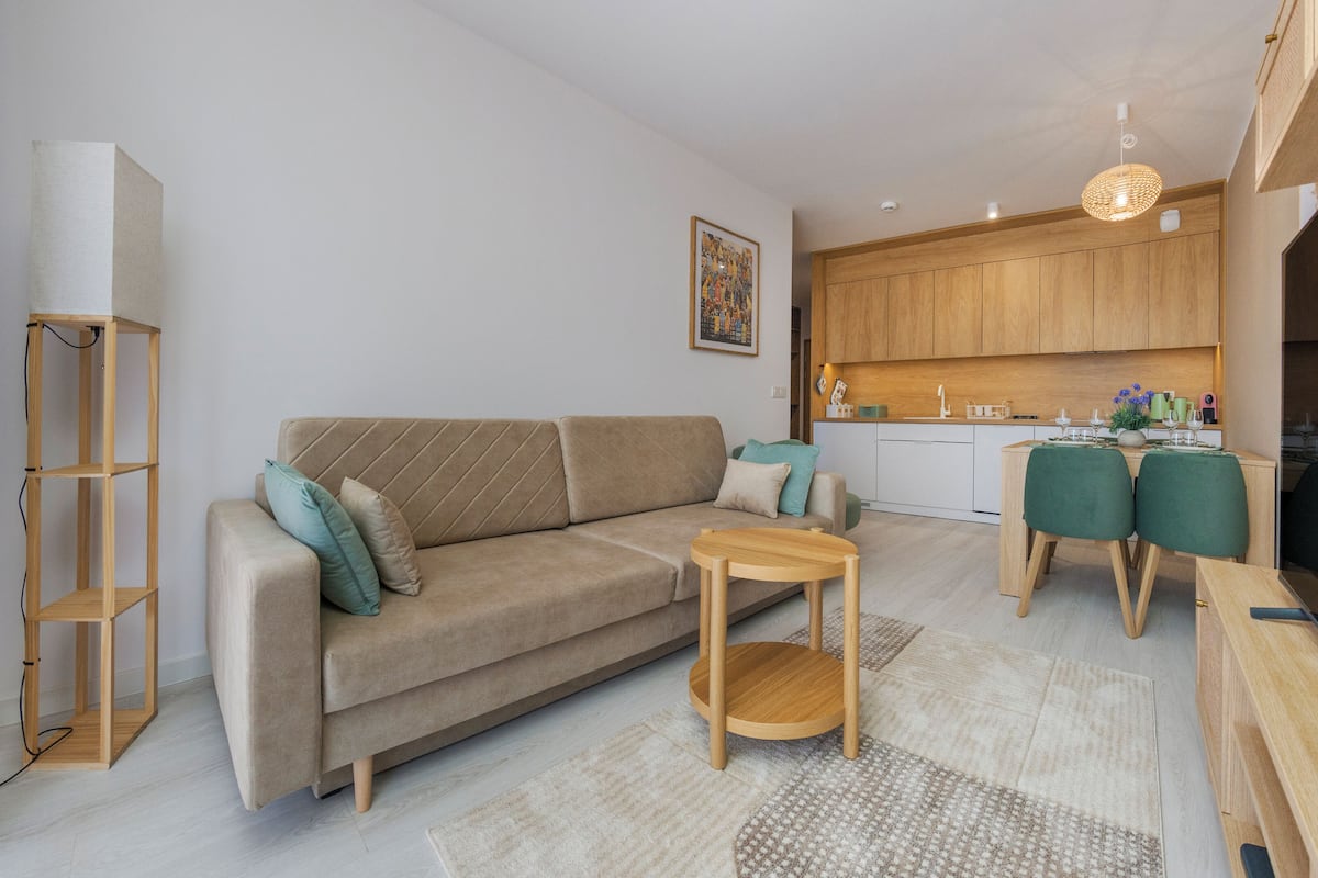 Un salon moderne comprenant un canapé, une petite table et un coin cuisine avec des meubles en bois et un ensemble de salle à manger.