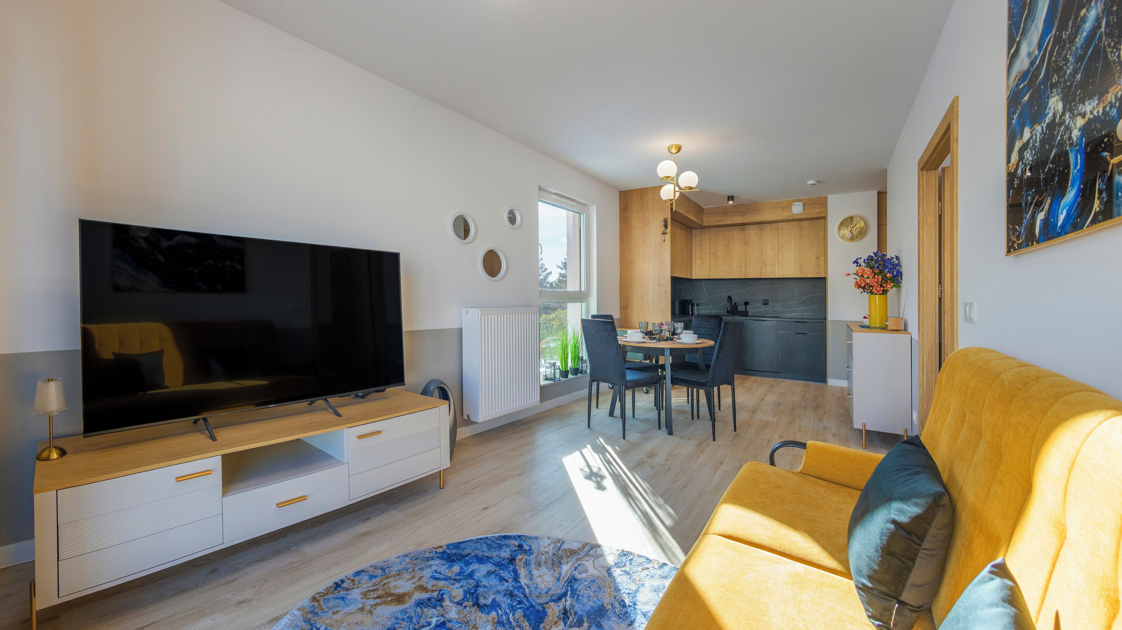 Ein modernes Wohnzimmer mit Flachbildfernseher, einer Couch und einem Essbereich mit Tisch und Stühlen.