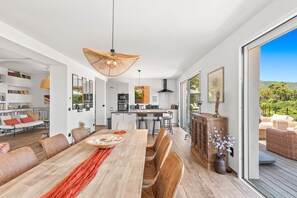 Un intérieur moderne comprenant un coin repas, une cuisine et un balcon aménagé avec du mobilier d’extérieur.