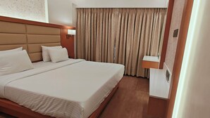 A hotel room with a large bed, a headboard, a bedside table, a lamp, and a curtain. - CIESTA SERENE (Navi Mumbai)