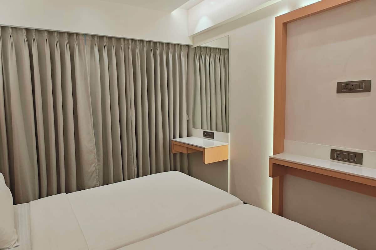 Una habitación de hotel con cama, mesita de noche, espejo y ventana con cortinas.