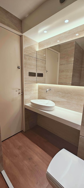 A modern bathroom with a white sink, a mirror, and a wooden floor. - CIESTA SERENE (Navi Mumbai)