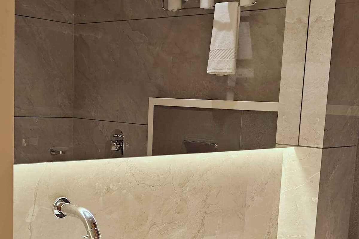 Un baño con un lavamanos ovalado grande, un espejo y un toallero con toallas.