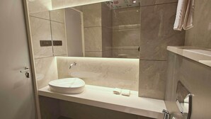 A modern bathroom with a large mirror, a sink, and a shower area. - CIESTA SERENE (Navi Mumbai)