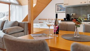 Una cucina moderna con travi in legno, un tavolo da pranzo con un sottopiatti, due bicchieri da vino, una bottiglia di vino e un vaso con fiori.