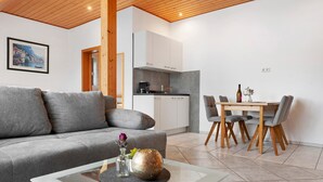 Un soggiorno moderno con un divano grigio, un tavolino in vetro e una zona pranzo con tavolo e sedie in legno.