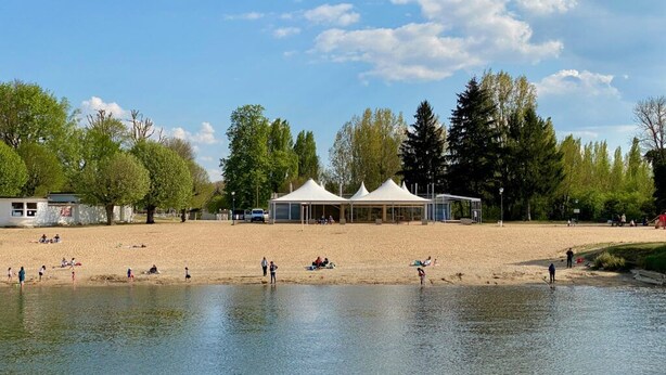 Ein Seeuferpark mit Sandstrand, Zelten und Bäumen.