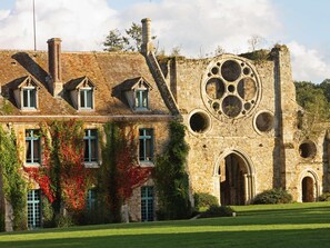 A historic building with a stone facade, multiple windows, and a large circular window. - Abbaye Des Vaux De Cernay (Cernay-la-Ville)