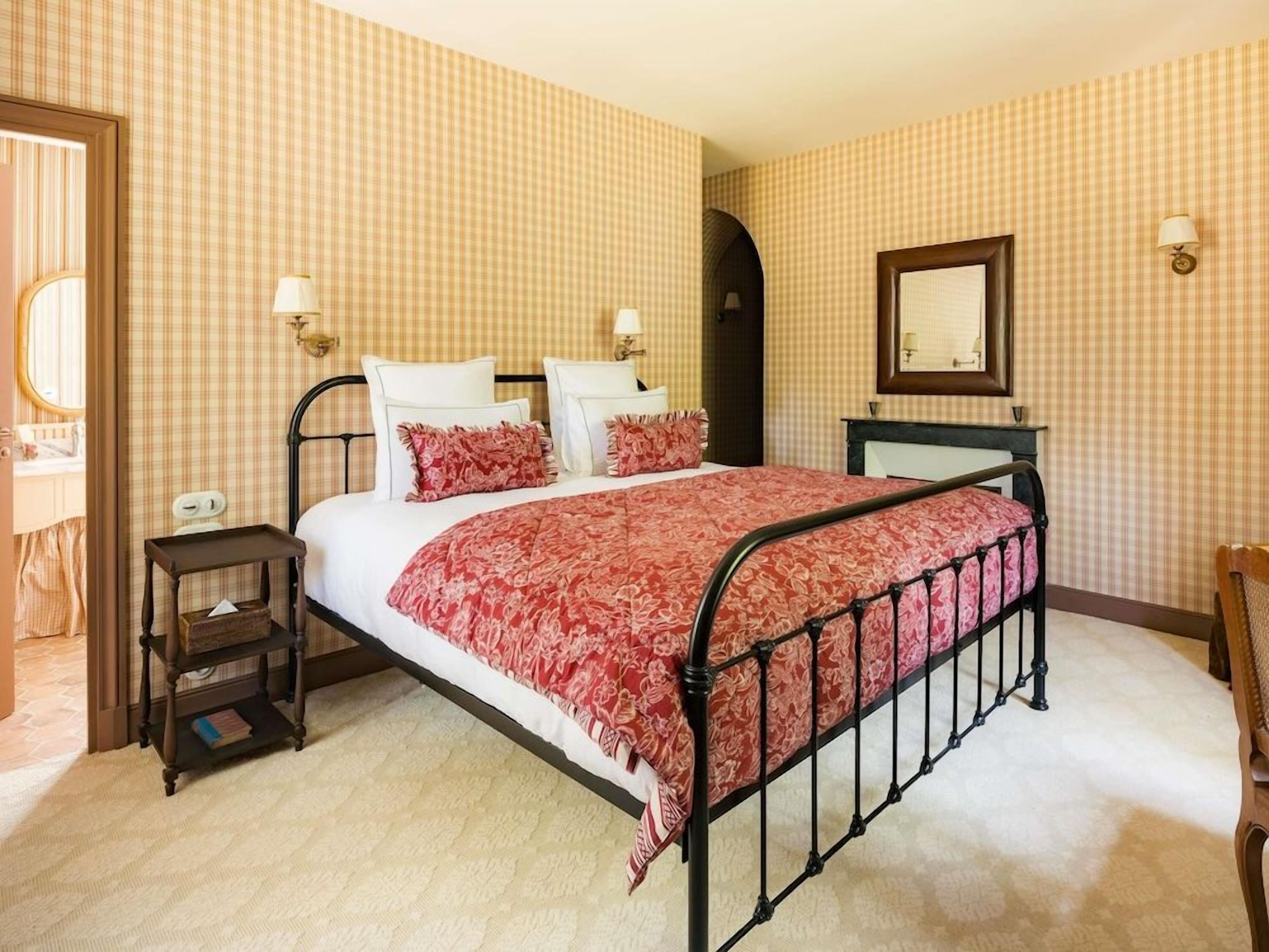 Une chambre à coucher avec un lit, des tables de chevet, un miroir et une porte.