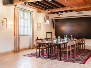 A conference room with a large table, chairs, and a projector screen.