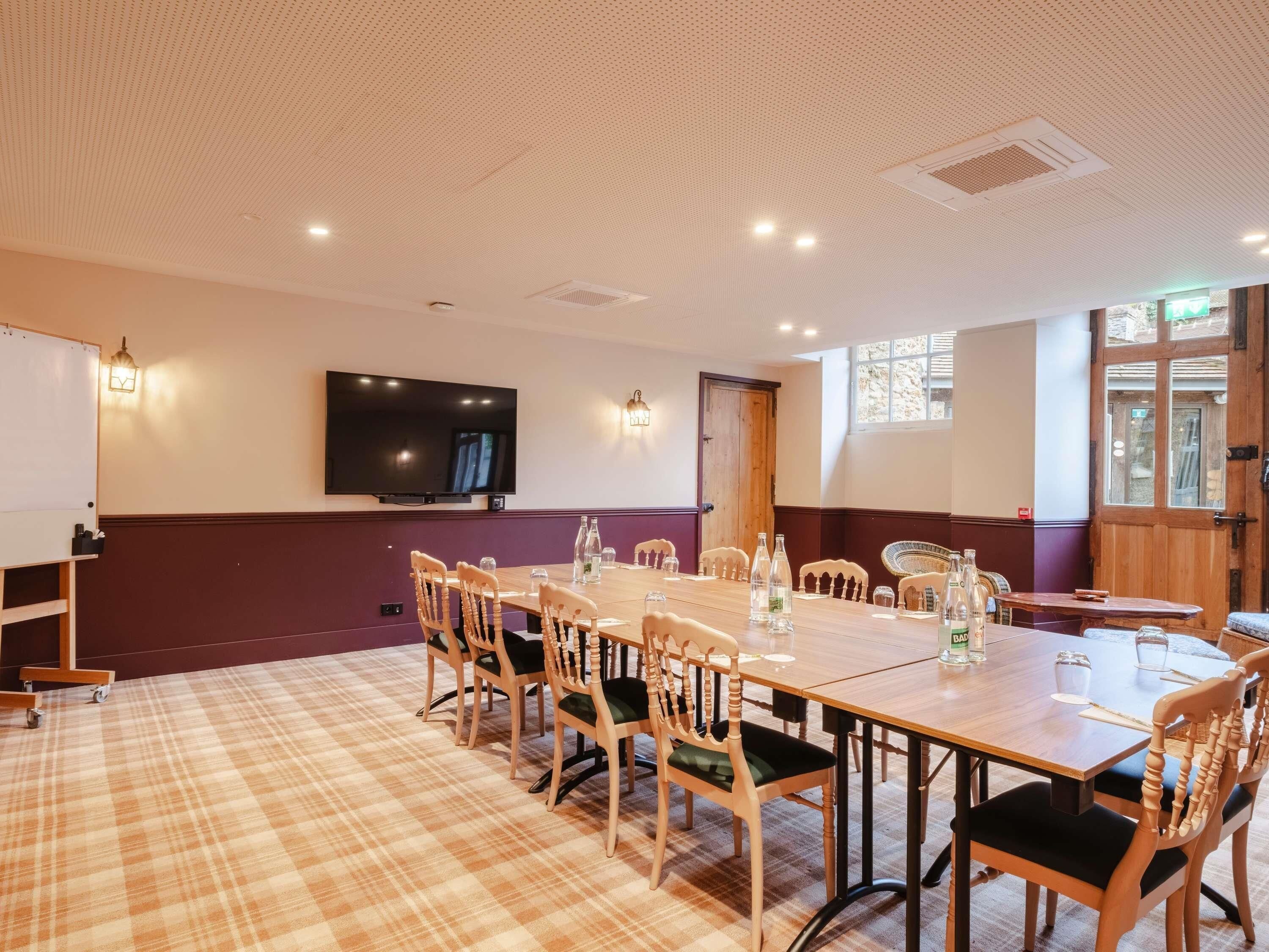 A conference room with a large table, chairs, a television, and a window.