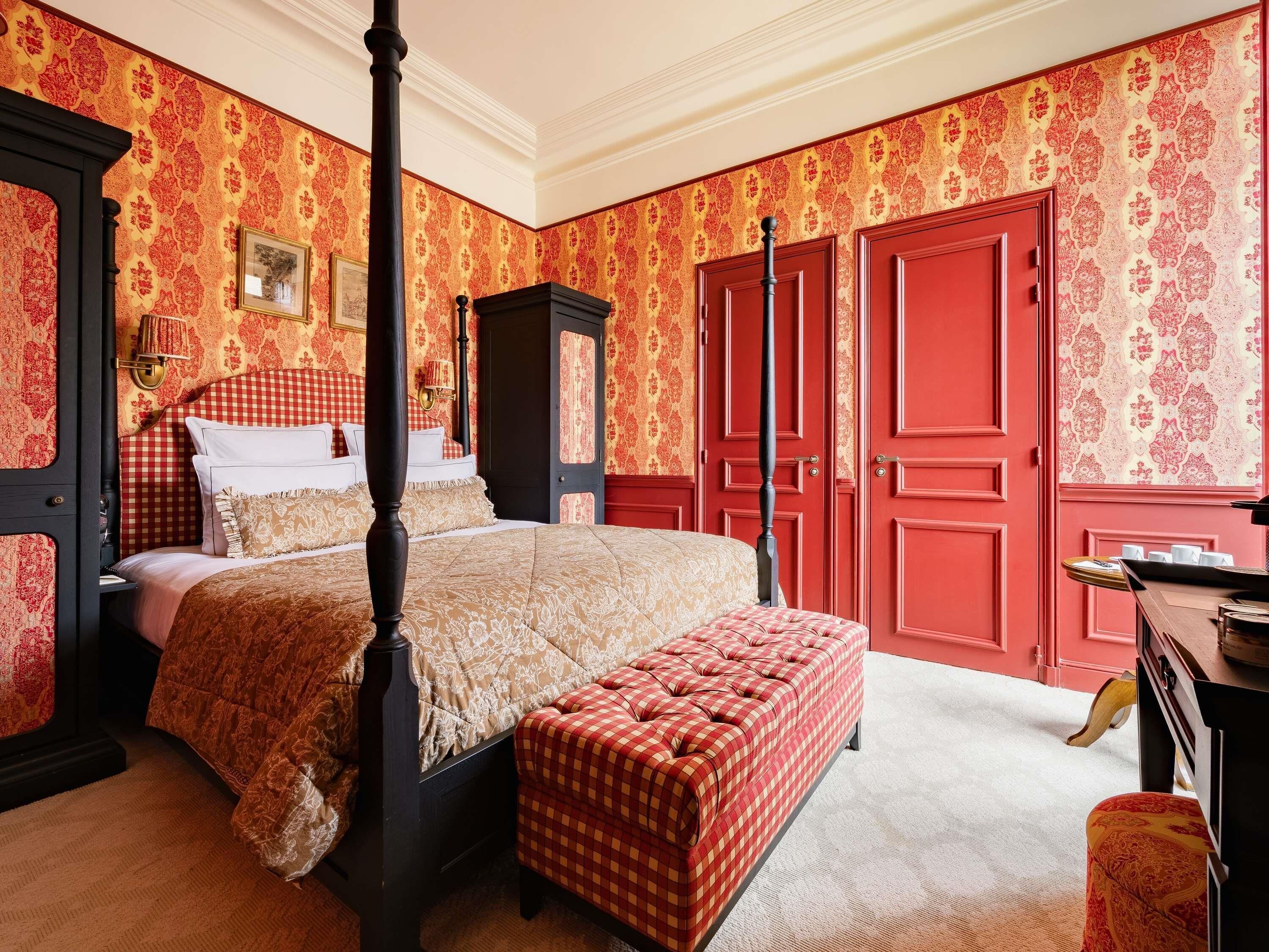 A four-poster bed with a checkered bench, a wardrobe, and a desk with a lamp.