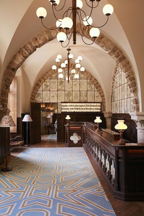 An interior with arched ceilings, a patterned carpet, and a reception desk with lamps. - Abbaye Des Vaux De Cernay (Cernay-la-Ville)