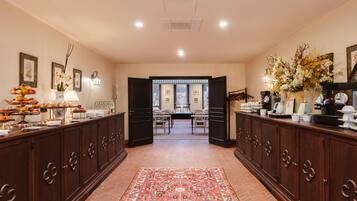 A hotel lobby with a buffet, a patterned rug, and a view through an open door to a dining area.