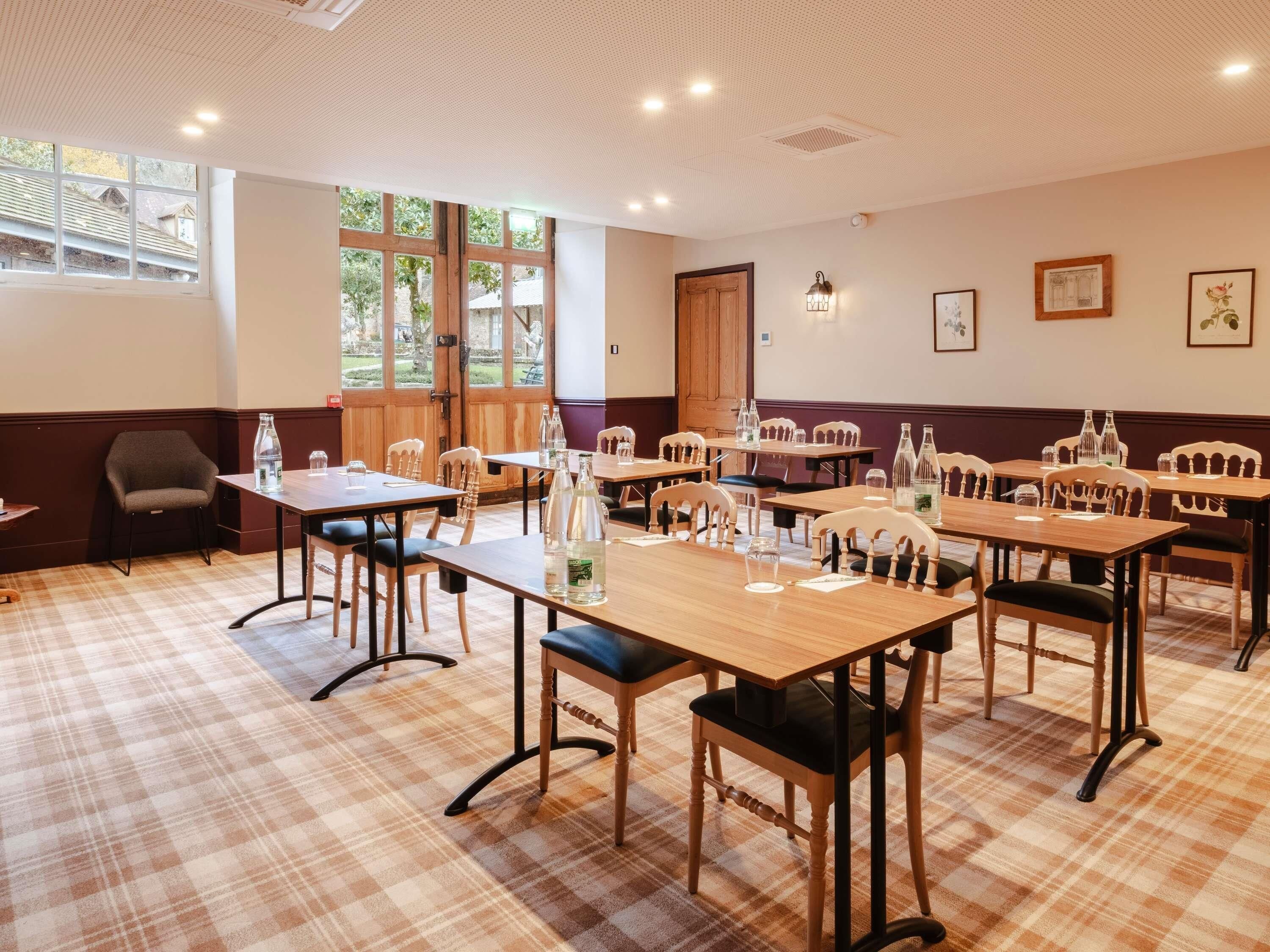Une salle à manger d’hôtel avec un sol à carreaux, des tables et des chaises en bois.
