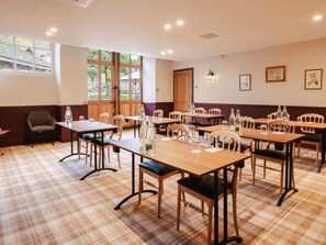 Une salle à manger d’hôtel avec un sol à carreaux, des tables et des chaises en bois.