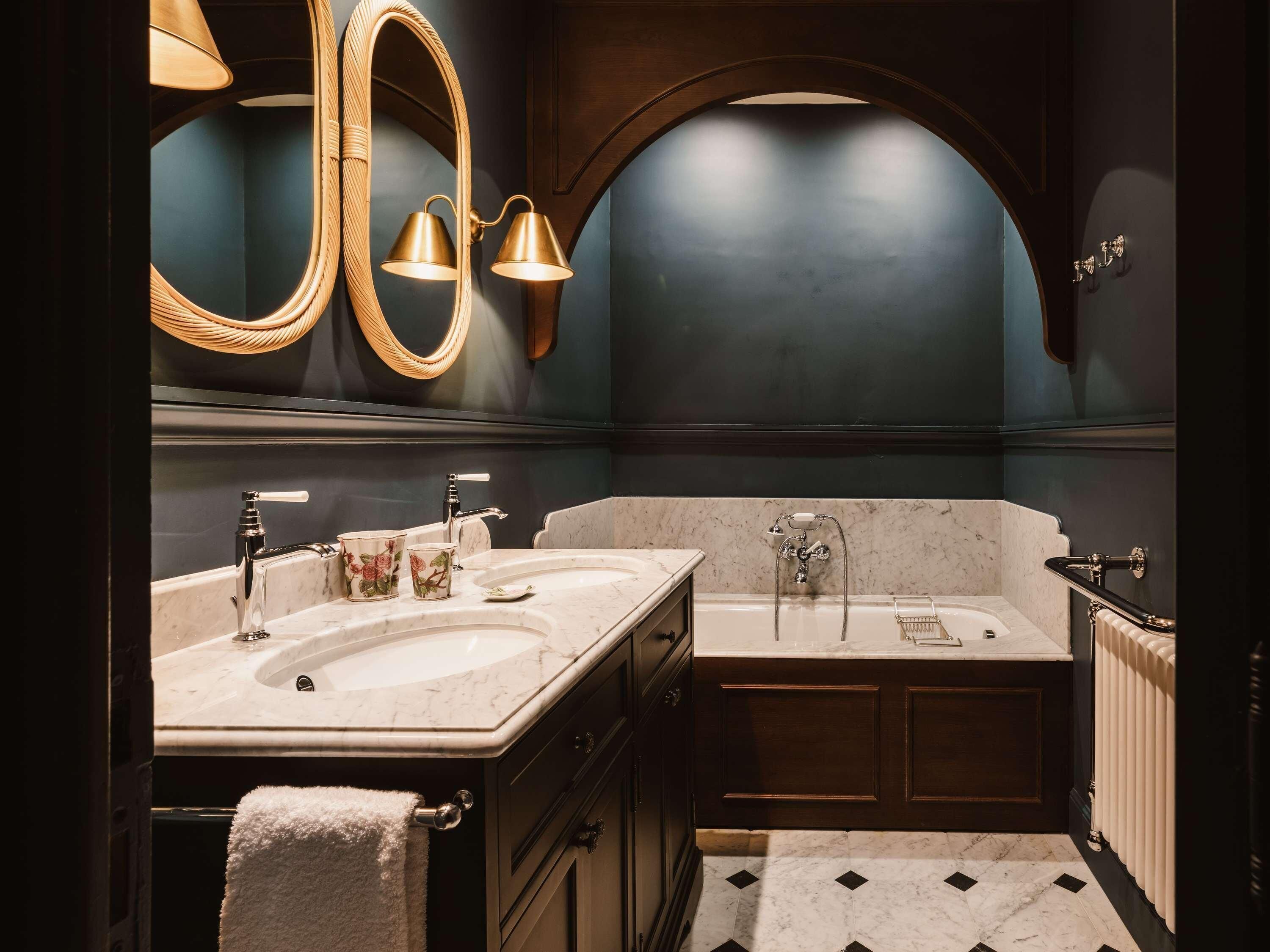 A bathroom with two sinks, a bathtub, a large mirror, and a towel rack.