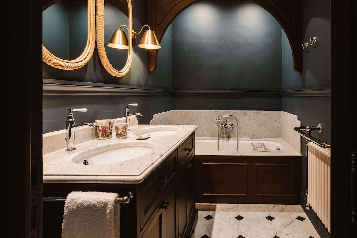 A bathroom with two sinks, a bathtub, a large mirror, and a towel rack.
