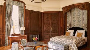Een klassieke kamer met een bed, een ronde tafel, stoelen, een bureau en een radiator.