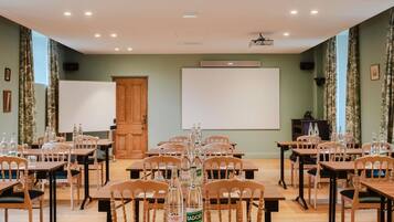 A conference room with tables, chairs, a projector, and a whiteboard.