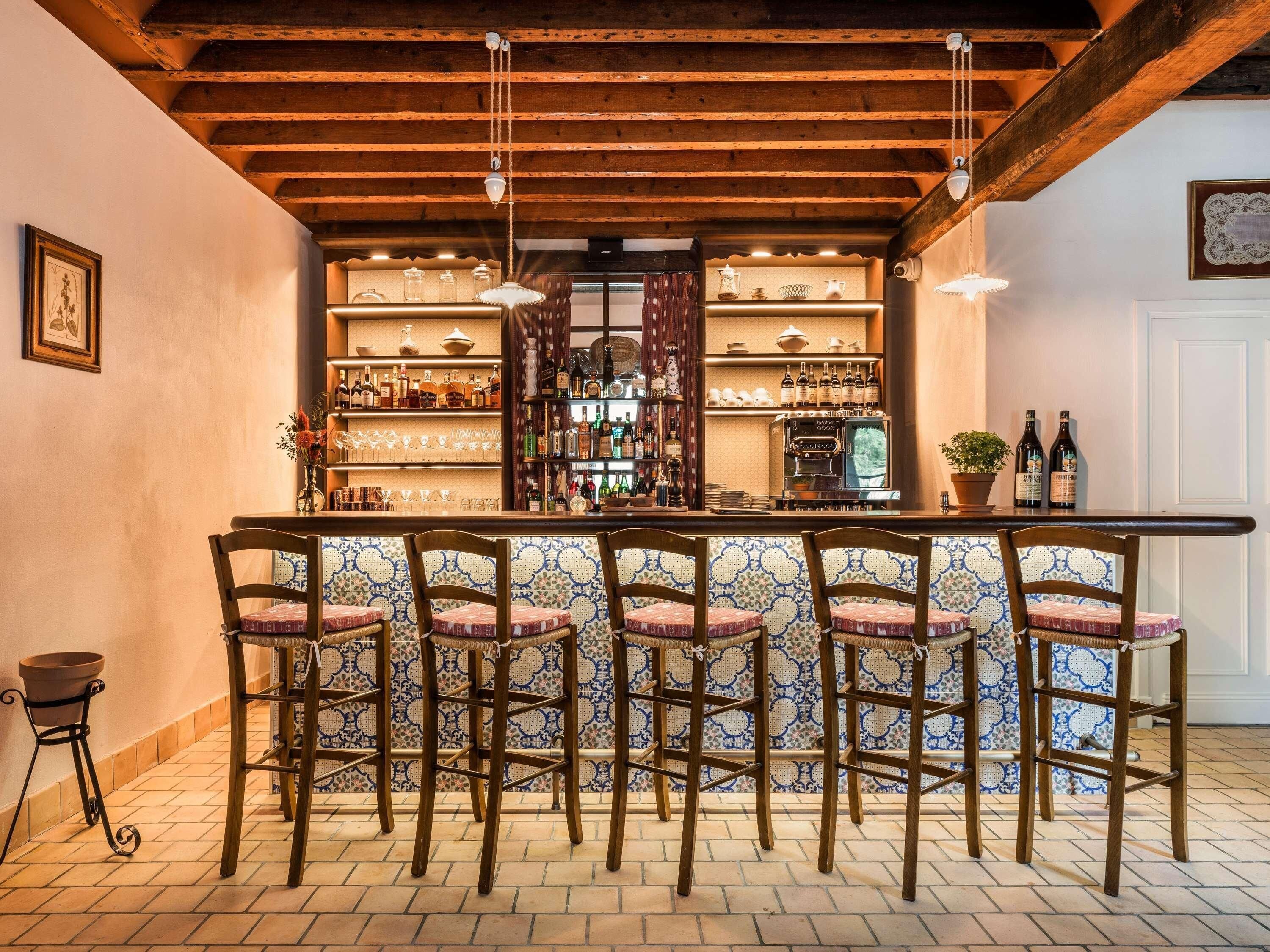 Een bar met houten balken, barstoelen, flessenkasten en een koffieapparaat.