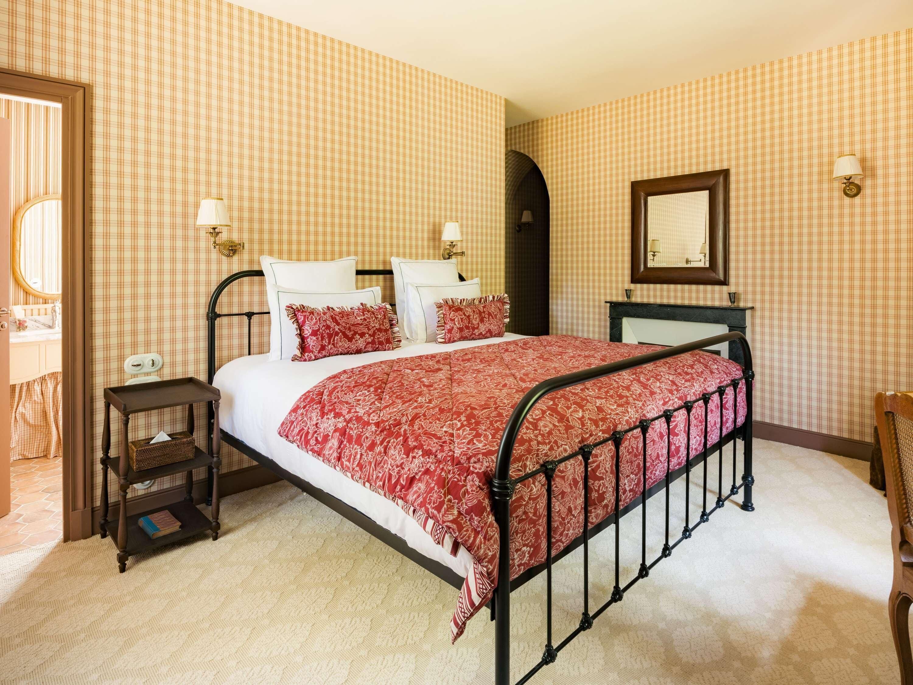 A bedroom with a bed, bedside tables, a dresser, a mirror, and a door.